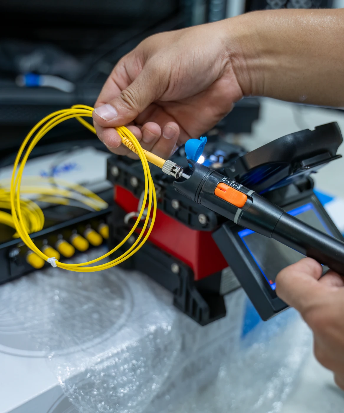 Hands working on fiber optic cable installation.
