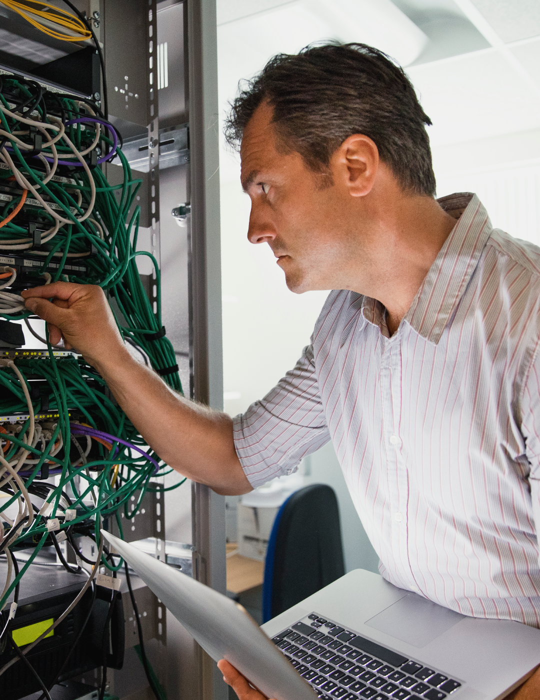 Man inspecting server cables with laptop.