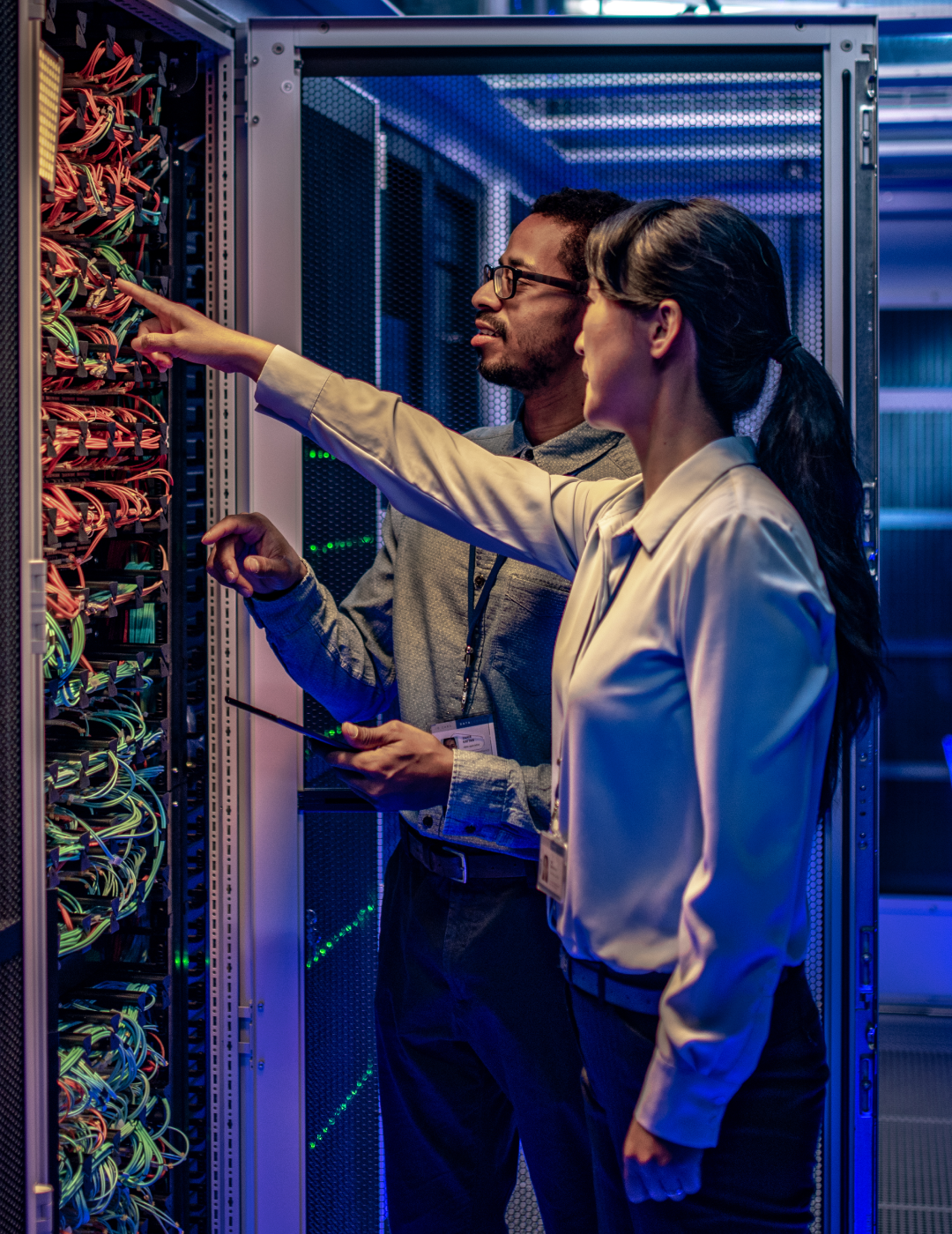Technicians inspecting server cables in data center.