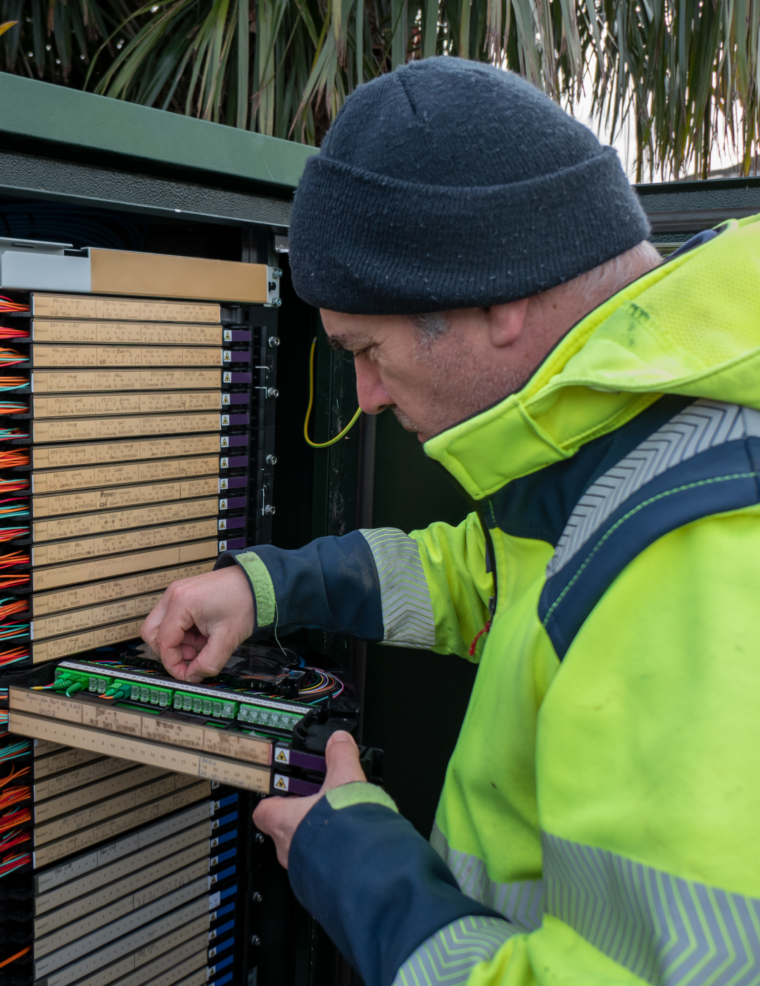 Technician working on electrical cabinet outdoors.