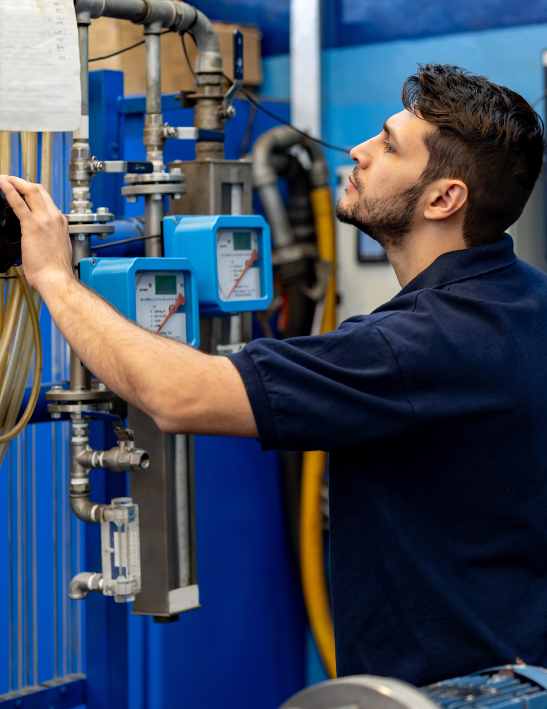 Technician adjusting industrial equipment in factory.