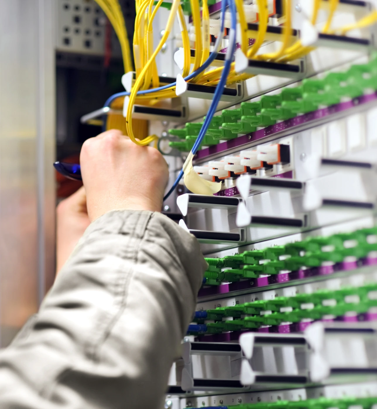 Person working on network cables in server.